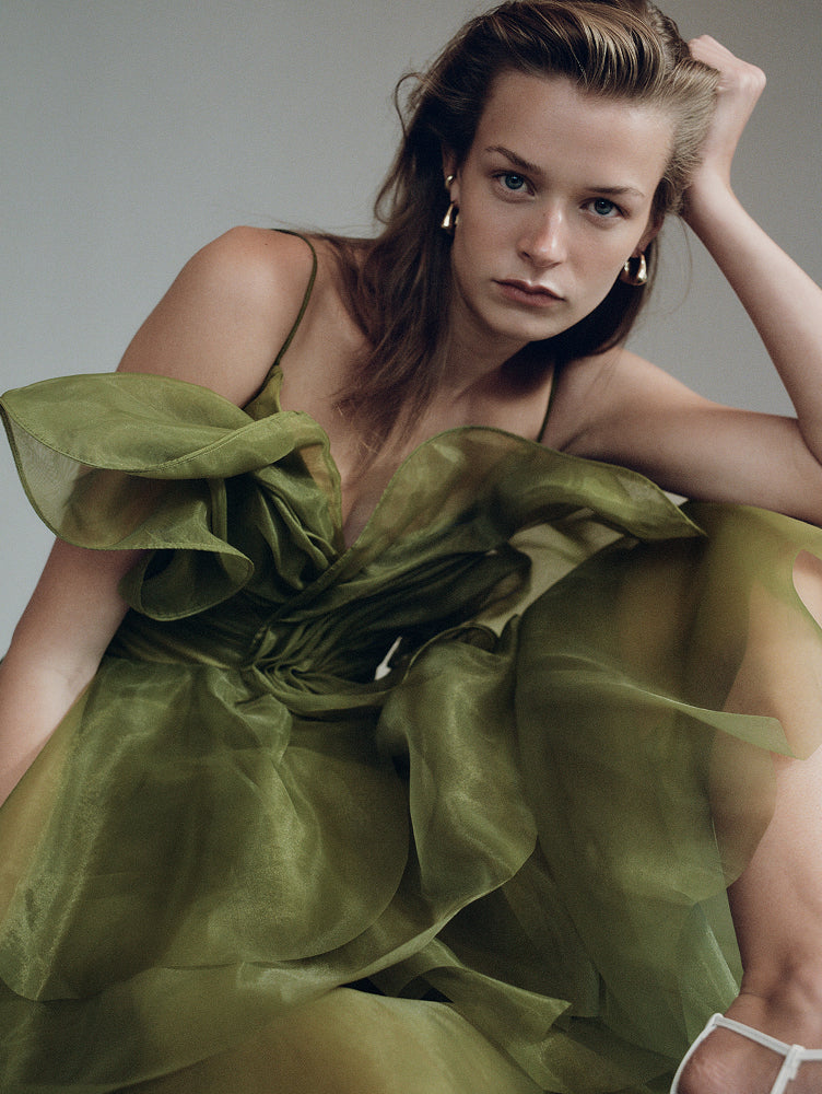 Aje campaign model wearing a sculptural olive dress